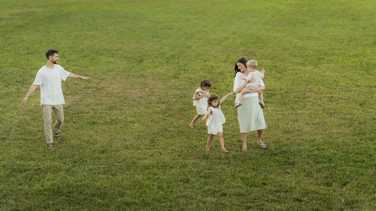 Family walking across a grassy field at sunset